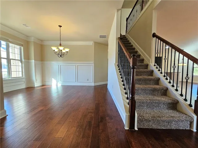 a view of an entryway with wooden floor staircase and a kitchen