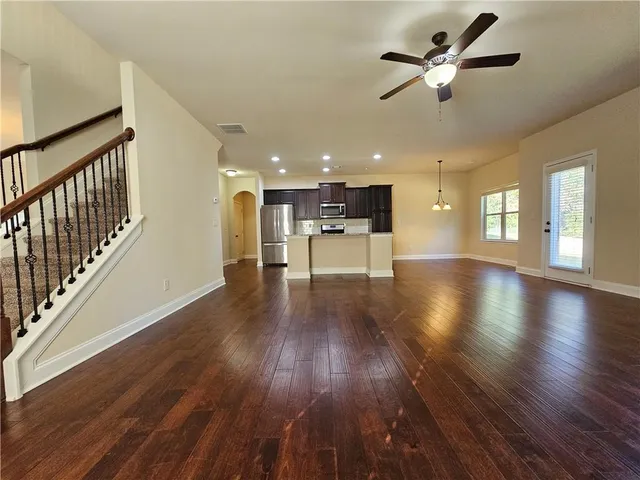 a view of a big room with wooden floor a ceiling fan and windows