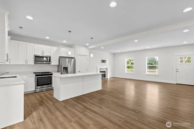 a view of kitchen with cabinets microwave and stove with wooden floor
