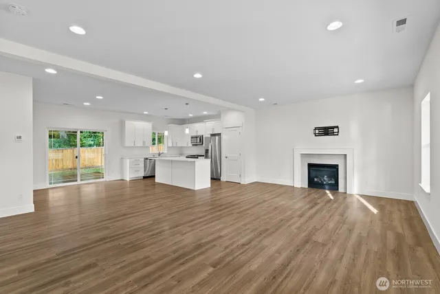 a view of an empty room with wooden floor and a fireplace