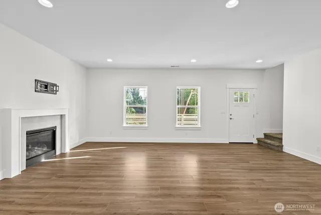 an empty room with wooden floor fireplace and windows