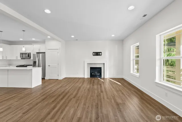 a view of an empty room with window and wooden floor