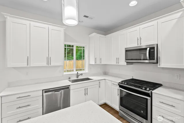 a kitchen with granite countertop white cabinets and stainless steel appliances