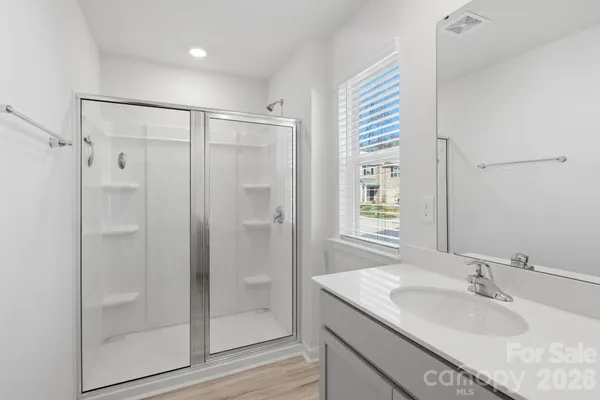a bathroom with a sink a mirror a glass door and shower