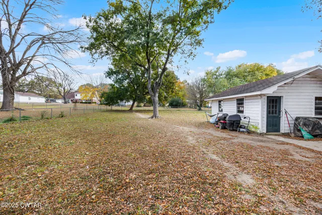 a view of a house with backyard and a tree