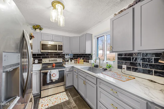 a kitchen with a sink stainless steel appliances and white cabinets
