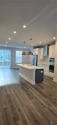 a large kitchen with stainless steel appliances a large counter top a stove and a wooden floors