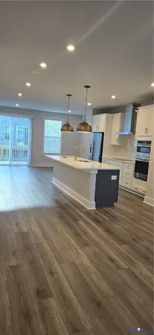 a living room with stainless steel appliances furniture a refrigerator and a kitchen view