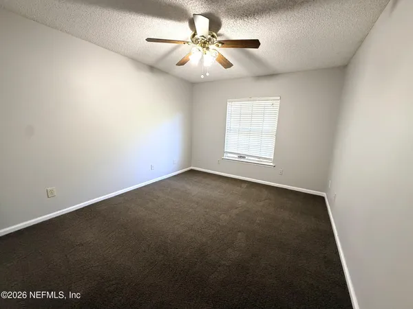 an empty room with windows and fan