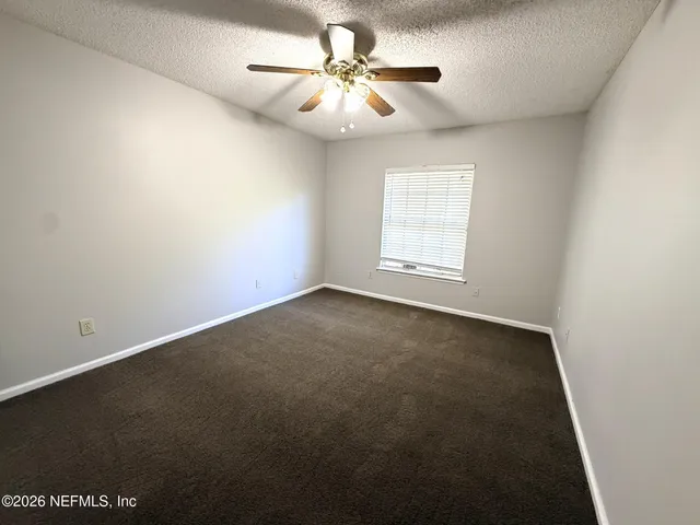 an empty room with windows and fan