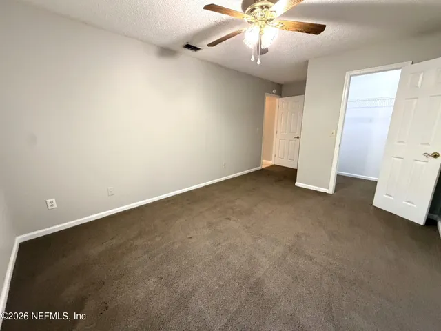 an empty room with a ceiling fan and carpet