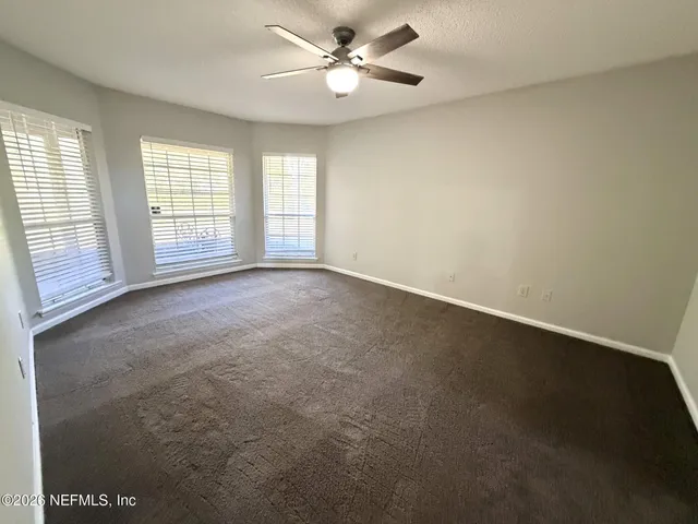 an empty room with windows and fan
