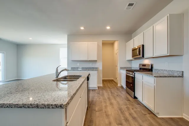 a kitchen with granite countertop a sink a stove top oven a counter space and cabinets