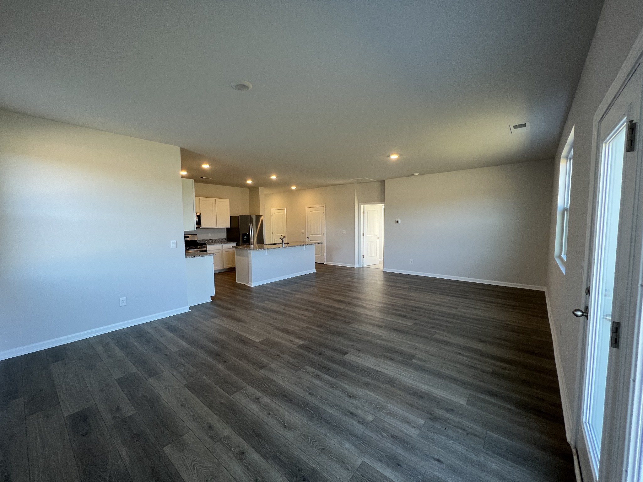 1703 Rylee Way Lebanon, TN 37087 - Photo 6 of 18 an empty room with wooden floor and kitchen view