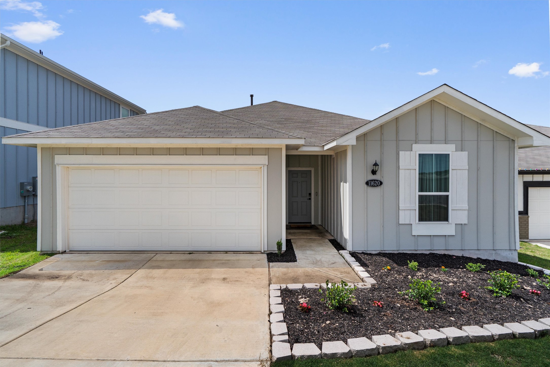 11620 Comano Drive Austin, TX 78747 - Photo 1 of 34 The property features a light gray exterior with white trim and a dark gray roof, a two-car garage, and a landscaped front yard with a walkway leading to the front entrance