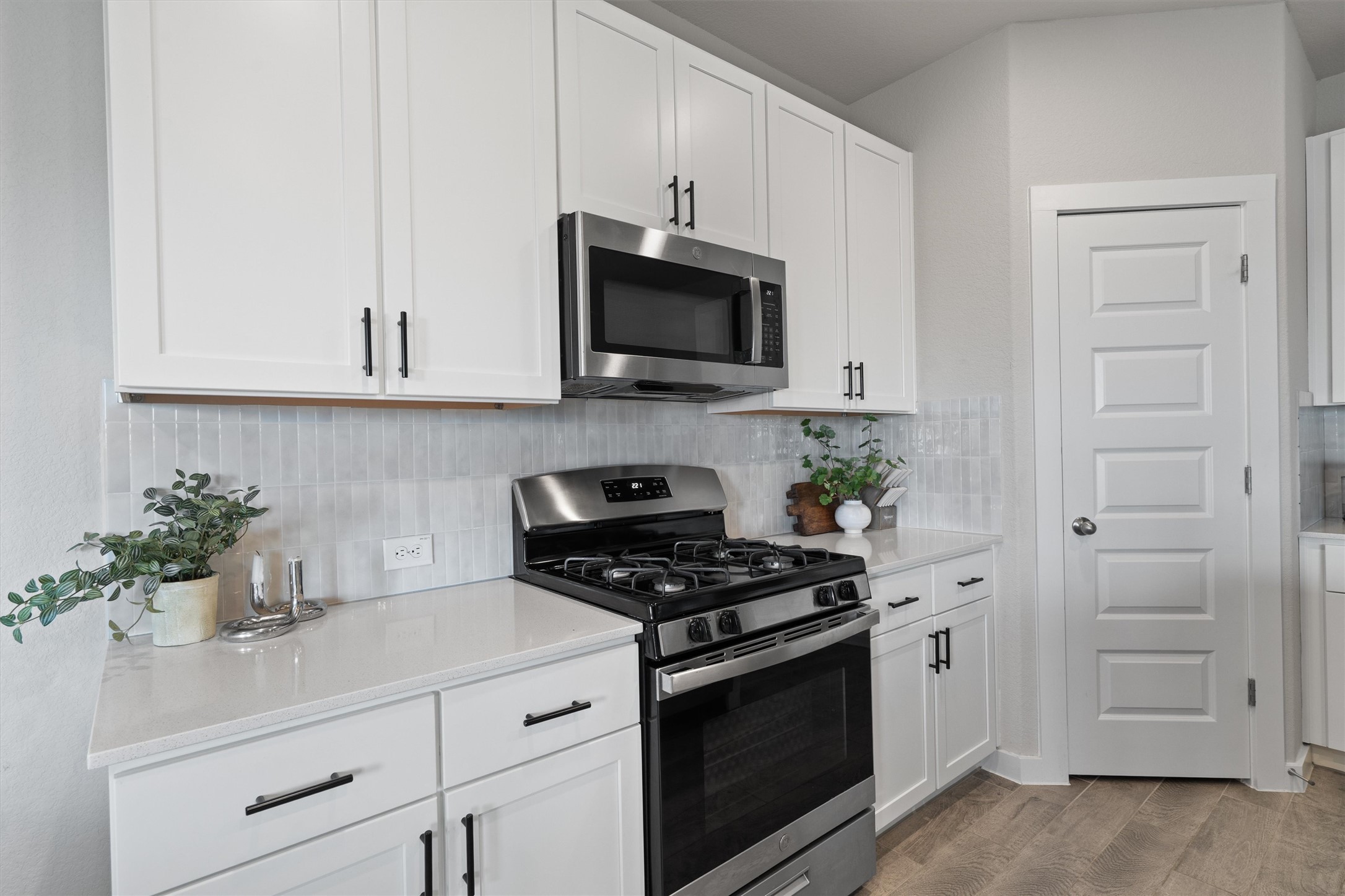 11620 Comano Drive Austin, TX 78747 - Photo 13 of 34 The kitchen features white cabinetry with dark hardware, a stainless steel microwave, and a stainless steel oven range