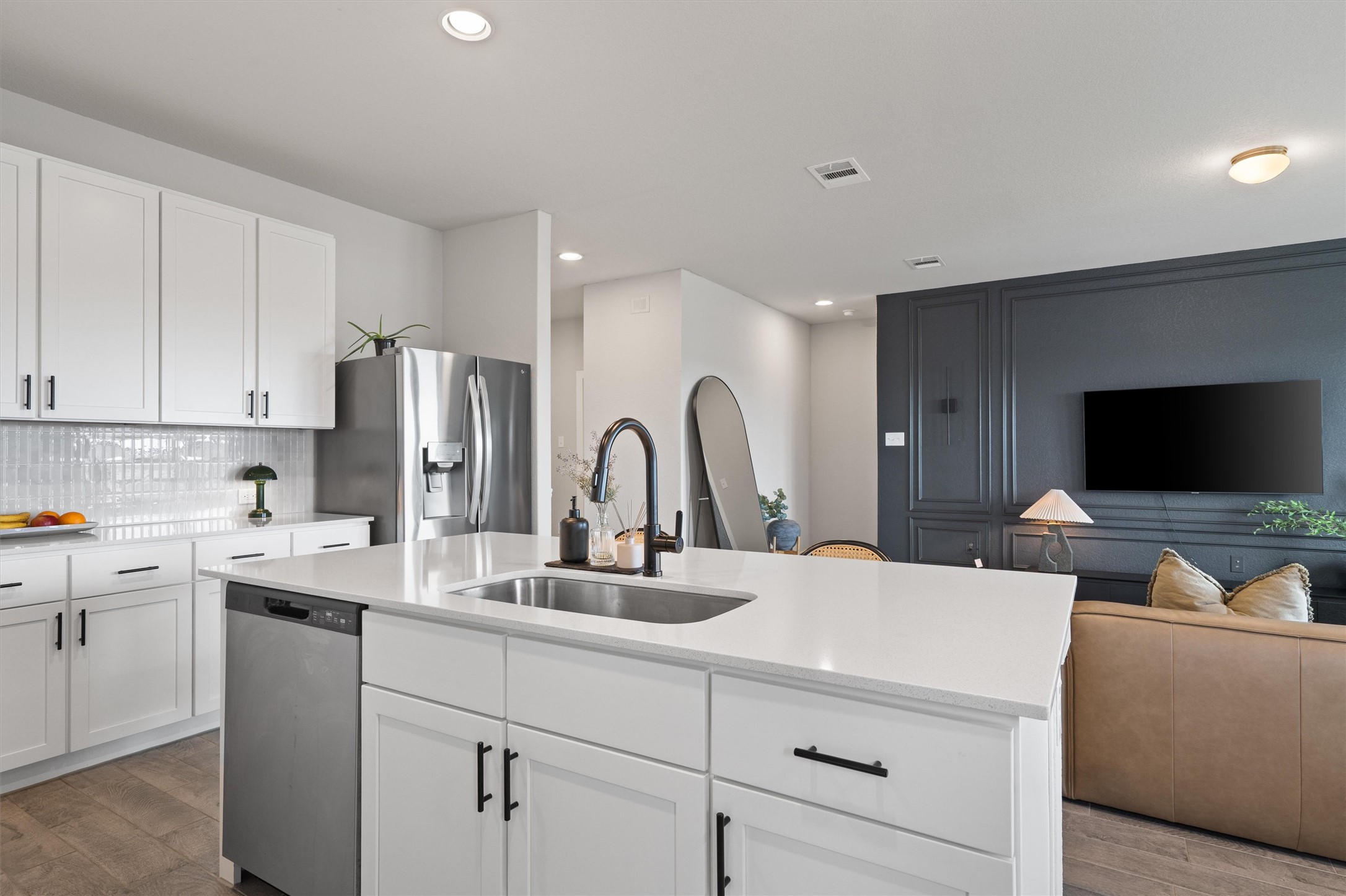 11620 Comano Drive Austin, TX 78747 - Photo 15 of 34 The kitchen features white cabinetry, a stainless steel dishwasher, a stainless steel refrigerator, and a white countertop with an undermount sink and a black faucet