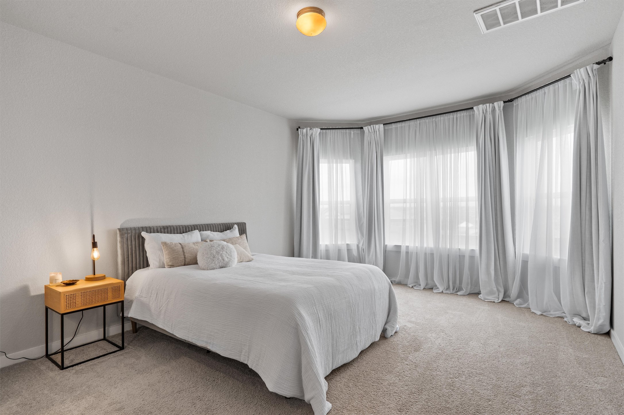 11620 Comano Drive Austin, TX 78747 - Photo 16 of 34 This room features light-colored carpet flooring, a ceiling light fixture, and large windows with sheer and opaque curtains