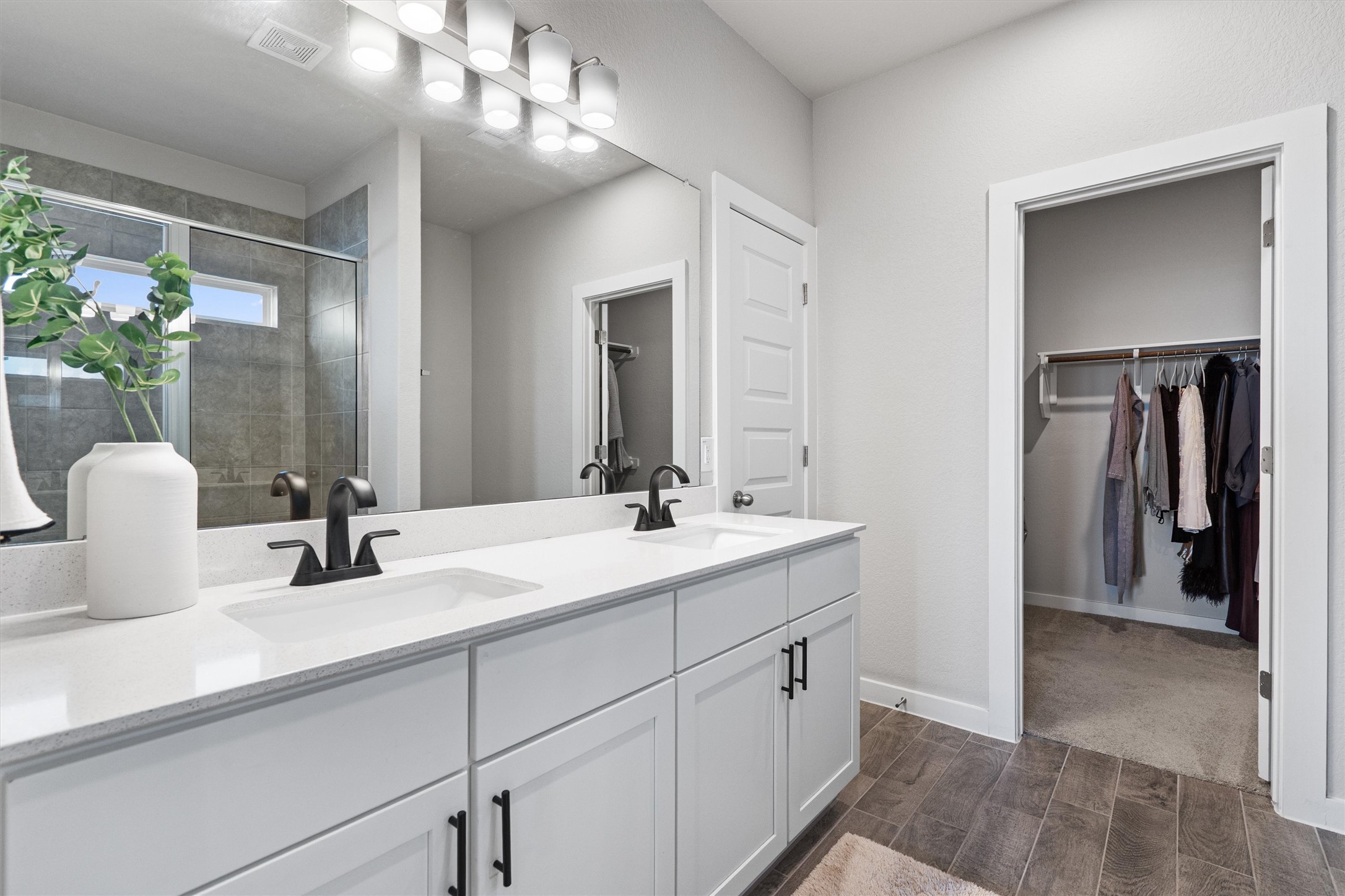 11620 Comano Drive Austin, TX 78747 - Photo 18 of 34 Bathroom featuring a dual vanity with white countertops, black faucets, and white cabinetry