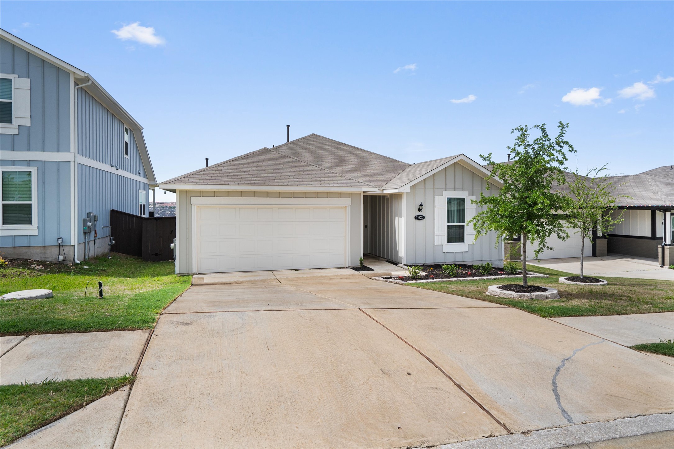 11620 Comano Drive Austin, TX 78747 - Photo 2 of 34 The property features an attached garage, a paved driveway, and manicured landscaping with young trees