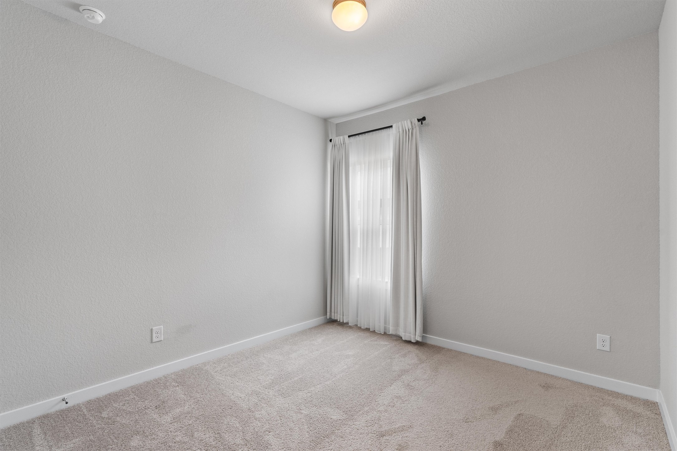 11620 Comano Drive Austin, TX 78747 - Photo 24 of 34 This room features light-colored walls, carpeted flooring, and a window with curtains
