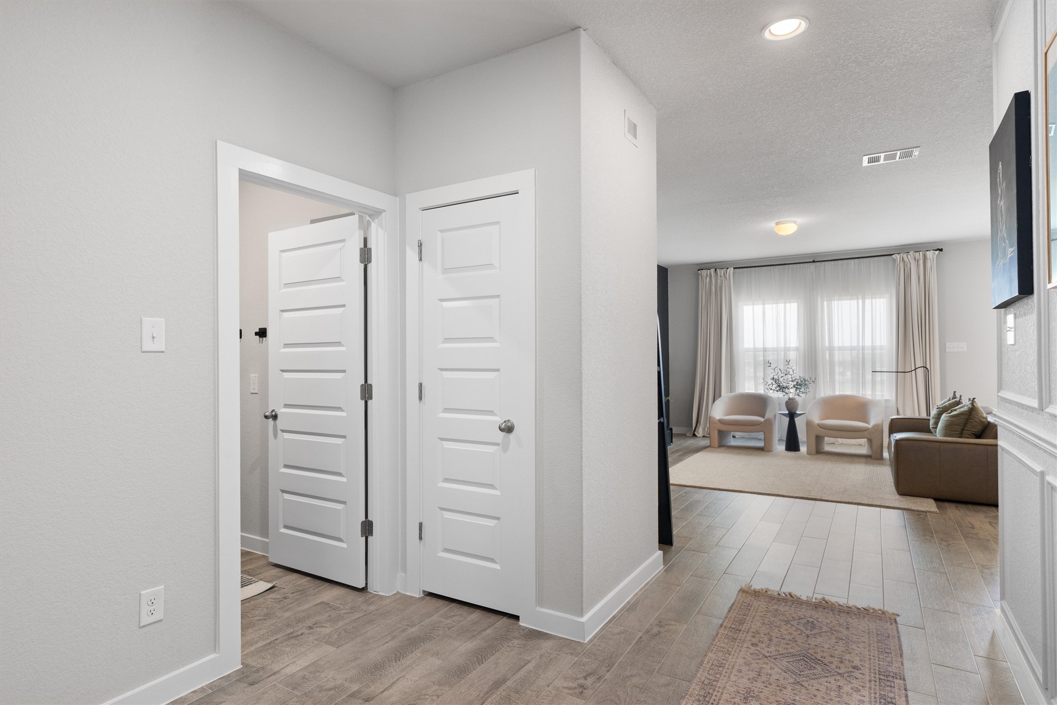 11620 Comano Drive Austin, TX 78747 - Photo 27 of 34 Entryway featuring light-colored walls and wood-look flooring, leading into a living space with ample natural light from large windows