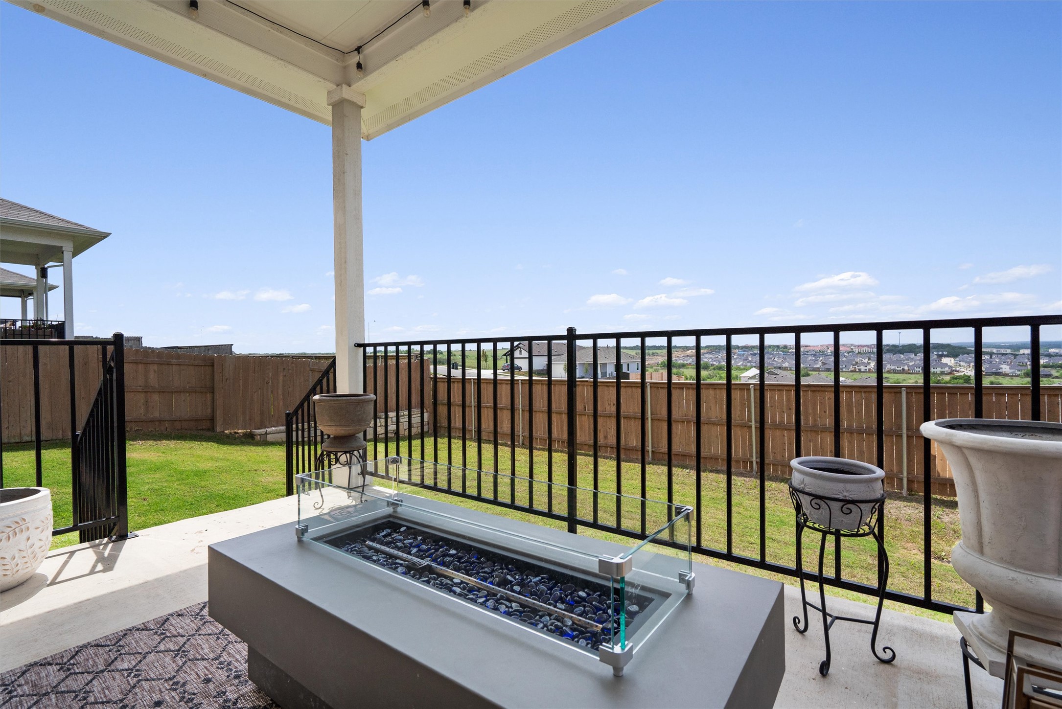 11620 Comano Drive Austin, TX 78747 - Photo 30 of 34 The property features a covered patio with a fire pit, a concrete slab, and a wrought iron fence overlooking a fenced yard