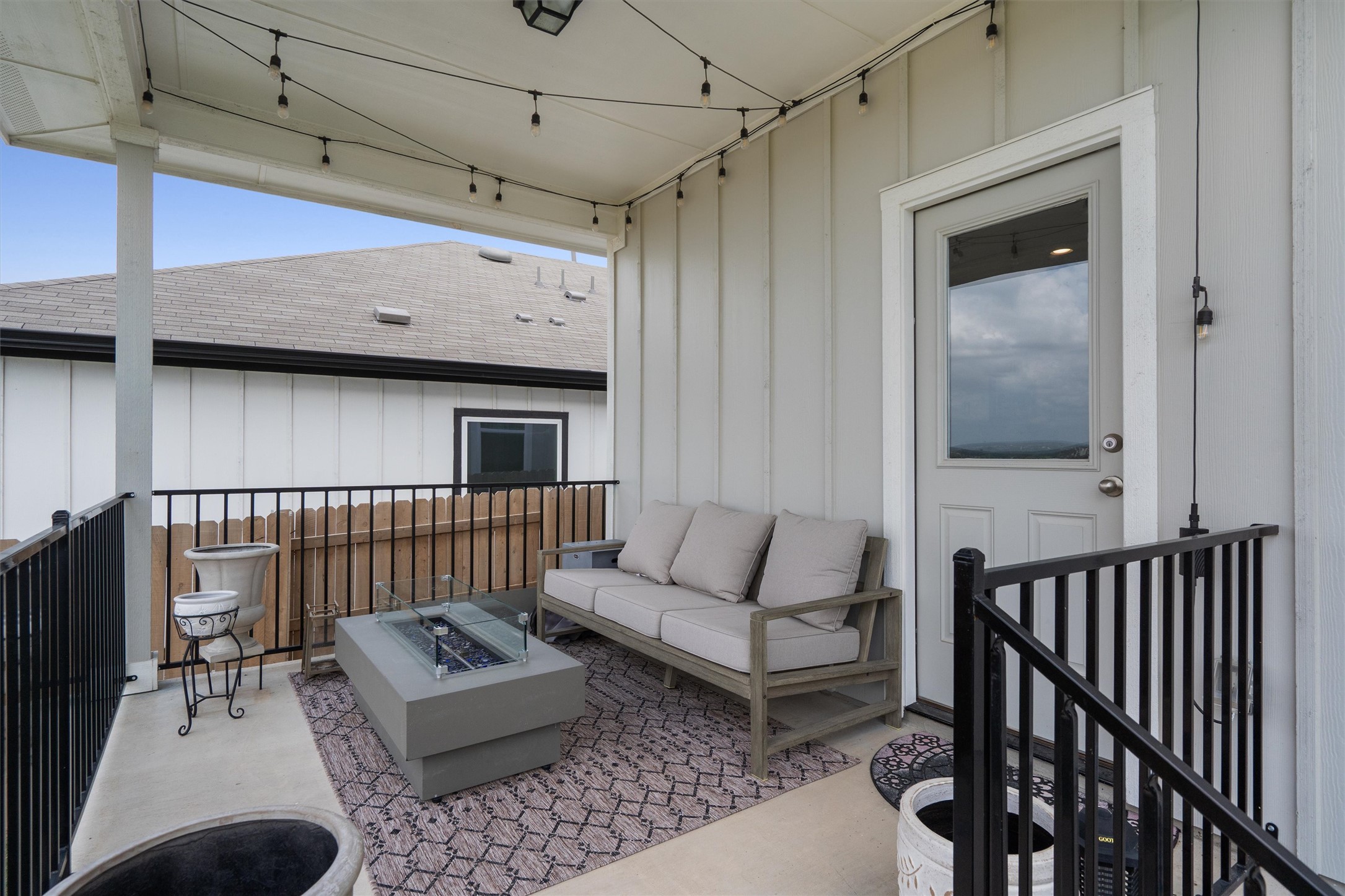 11620 Comano Drive Austin, TX 78747 - Photo 31 of 34 Inviting covered patio with string lights, featuring a sofa with cushions and a central fire pit