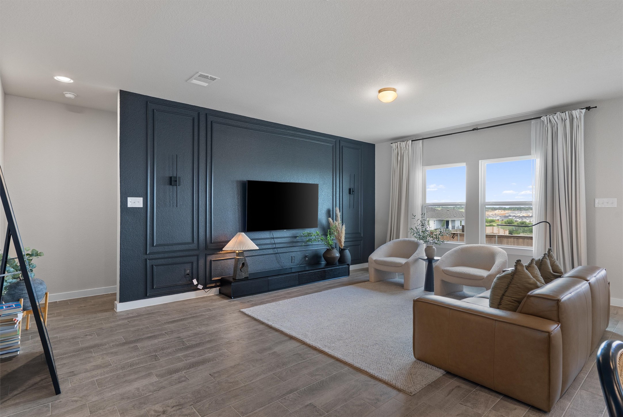 11620 Comano Drive Austin, TX 78747 - Photo 5 of 34 The living area features a decorative accent wall, wood-look tile flooring, and two large windows providing natural light