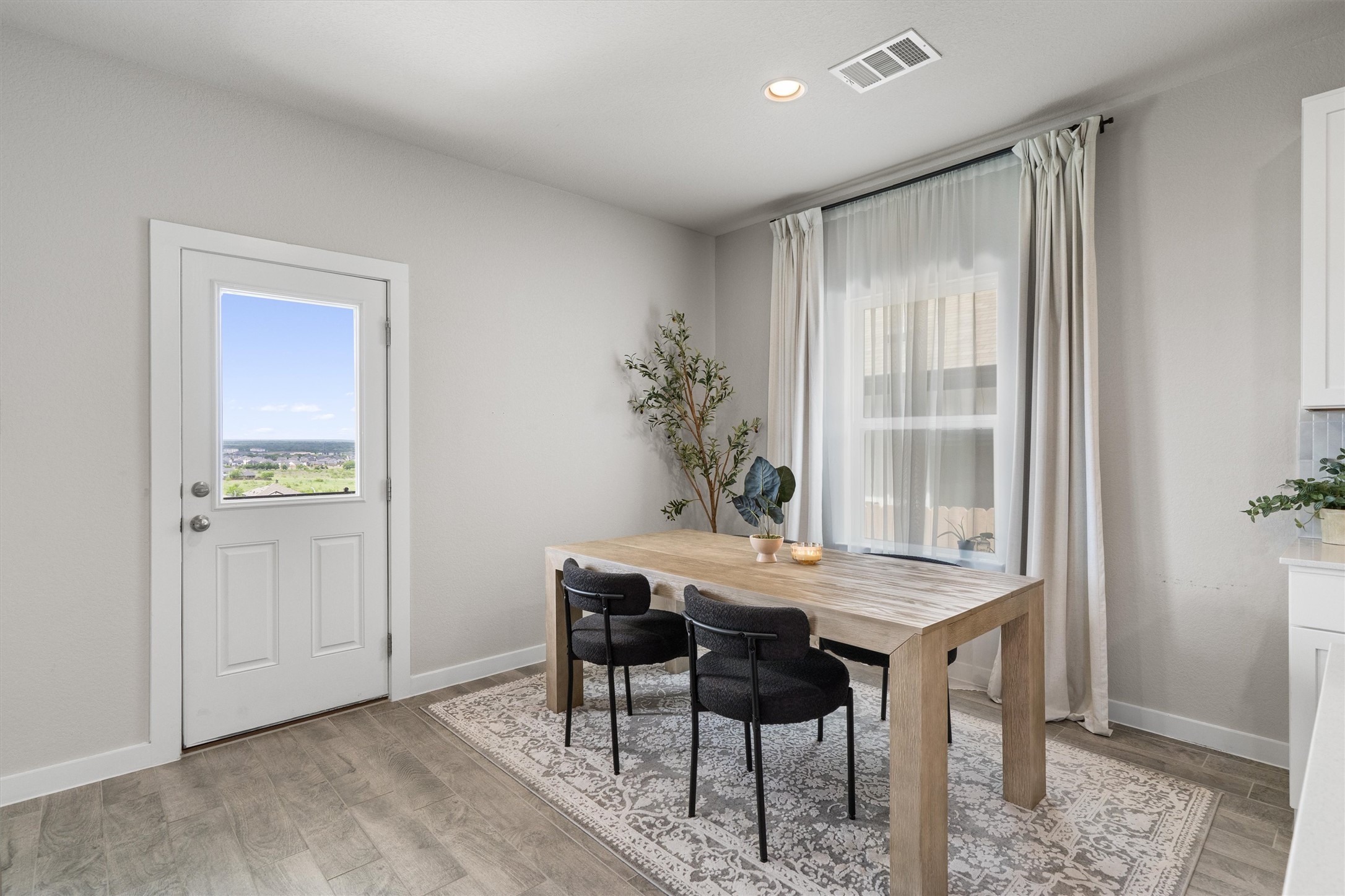 11620 Comano Drive Austin, TX 78747 - Photo 8 of 34 This bright dining area features light-toned flooring, a window with sheer and blackout curtains, and a door with an inset window offering expansive views