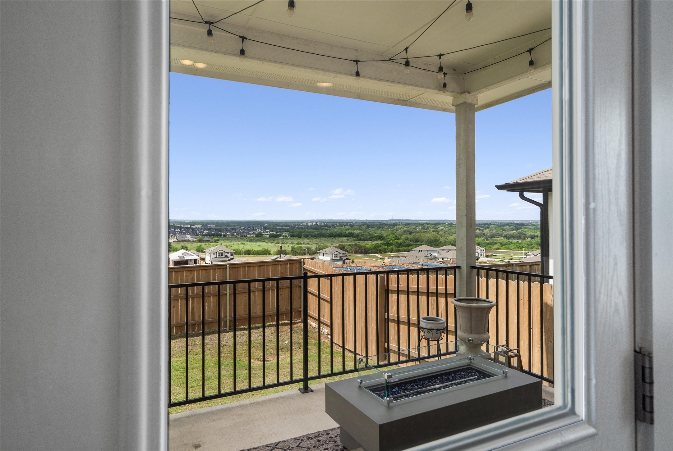 11620 Comano Drive Austin, TX 78747 - Photo 9 of 34 The property features a covered patio with string lights and a fire pit, offering expansive views of the surrounding landscape
