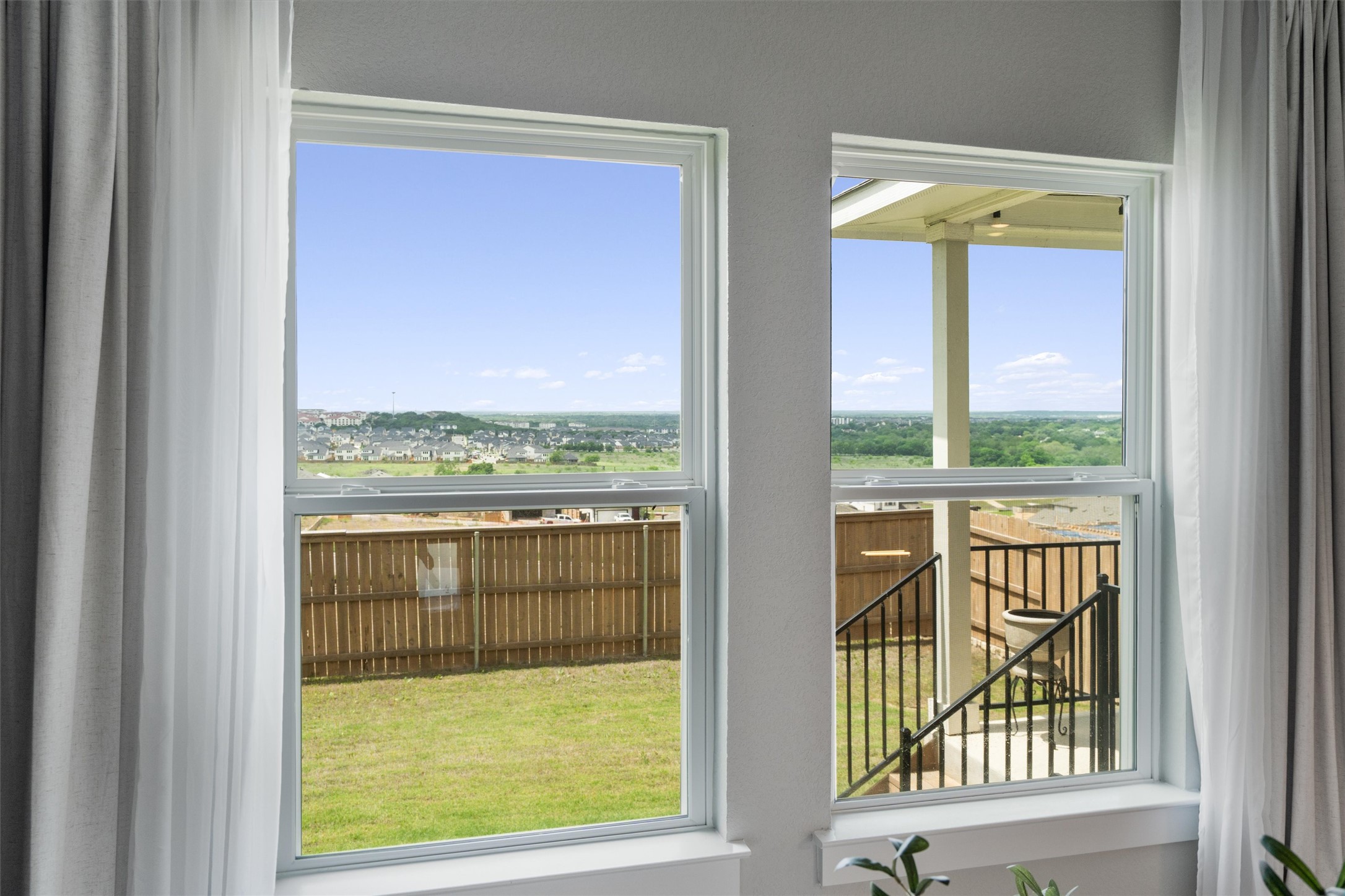 11620 Comano Drive Austin, TX 78747 - Photo 10 of 34 The property features large windows with white frames, offering expansive views of the surrounding landscape and distant structures