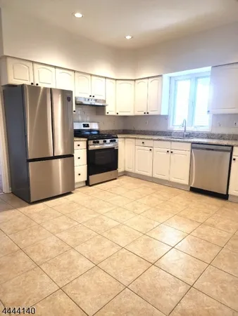 a large kitchen with granite countertop a refrigerator and a stove top oven