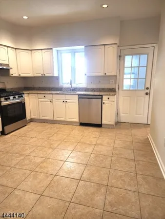 a large kitchen with a stove a sink a window and cabinets