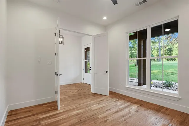 an empty room with wooden floor and windows
