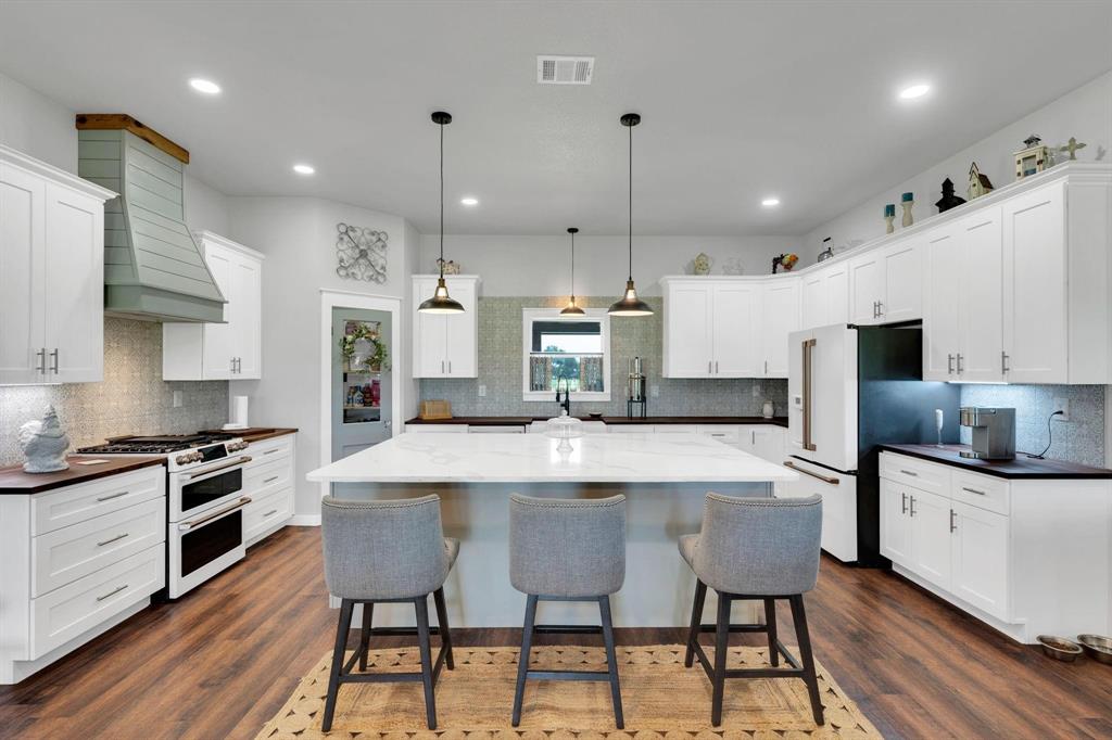 1467 Brown Road Palo Pinto, TX 76484 - Photo 17 of 38 a kitchen with stainless steel appliances kitchen island granite countertop a stove a sink a kitchen island with chairs and white cabinets