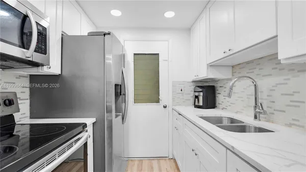 a kitchen with stainless steel appliances granite countertop a sink and a refrigerator