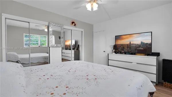 a bedroom with a bed a flat screen tv and balcony view