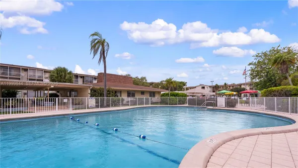 a view of a swimming pool with a lounge chair and palm trees