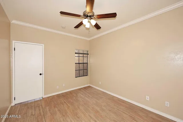 an empty room with wooden floor chandelier fan and windows