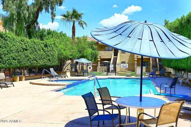 a view of pool with table and chairs under an umbrella