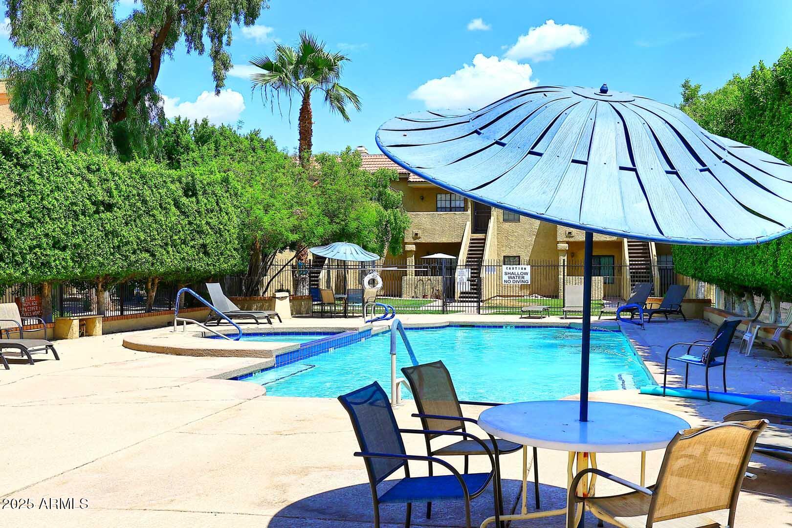 1126 West Elliot Road, Unit 1040 Chandler, AZ 85224 - Photo 7 of 25 a view of pool with table and chairs under an umbrella