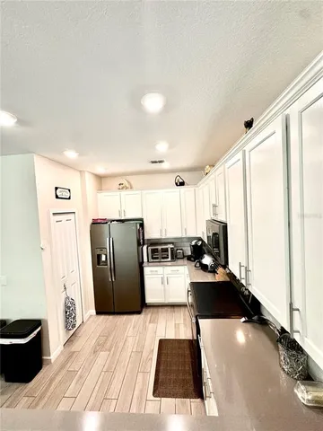 a kitchen with stainless steel appliances granite countertop a refrigerator a stove a sink and white cabinets with wooden floor