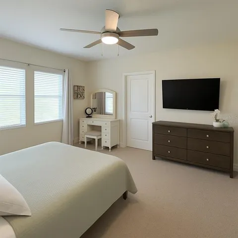 a spacious bedroom with a bed and a flat screen tv