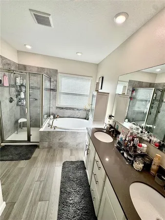 a spacious bathroom with a double vanity sink a toilet mirror and a bathtub