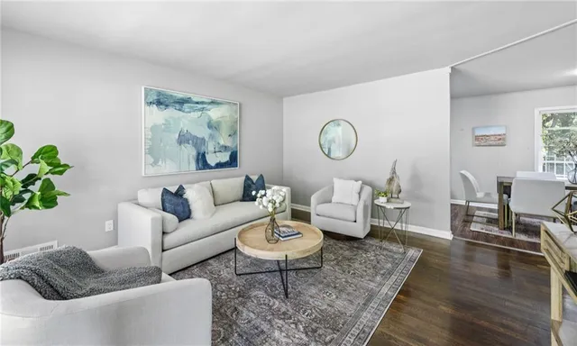 a living room with furniture a rug a lamp and wooden floor