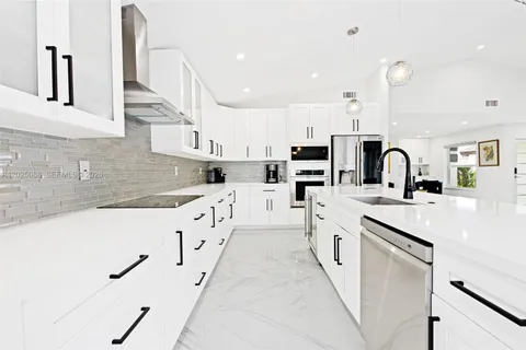 a large kitchen with stainless steel appliances kitchen island granite countertop a sink and cabinets