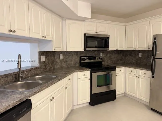 a kitchen with granite countertop white cabinets and stainless steel appliances