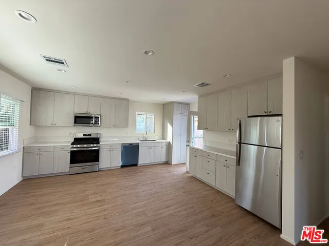 a kitchen with granite countertop a refrigerator stove and wooden floor