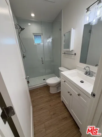 a bathroom with a sink a toilet a mirror and shower